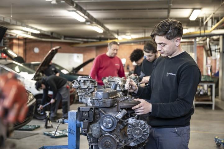 Jongen is aan het werken aan een automotor in een klas van Stedelijk Lyceum Zuid.