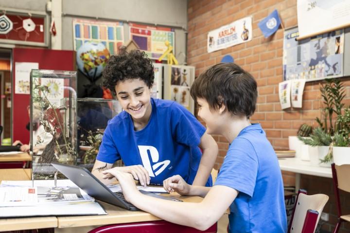 Twee jongens zoeken iets op de computer op in een klas van Stedelijk Lyceum Zuid.